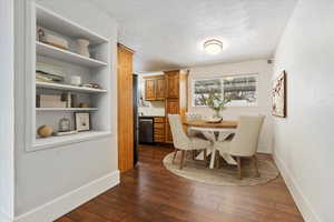 Dining space featuring dark wood-type flooring, a textured ceiling, and baseboards