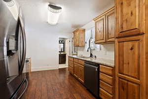 Kitchen featuring tasteful backsplash, a sink, dark wood finished floors, baseboards, and appliances with stainless steel finishes
