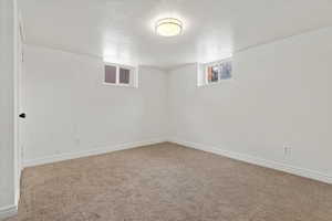 Basement with baseboards, carpet flooring, and a textured ceiling