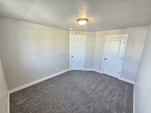 Empty room featuring baseboards, visible vents, carpet floors, and a textured ceiling