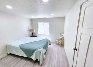 Bedroom featuring a textured ceiling, light wood-type flooring, baseboards, recessed lighting, and visible vents