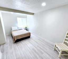 Bedroom with baseboards, wood finished floors, a textured ceiling, and recessed lighting