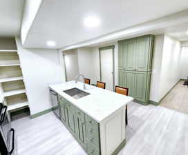 Kitchen with a peninsula, dishwasher, green cabinets, and a sink
