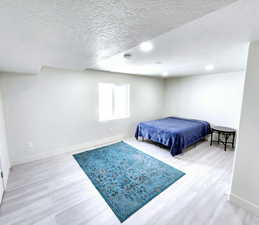 Bedroom featuring baseboards, wood finished floors, and a textured ceiling