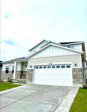 View of front of house featuring stone siding, board and batten siding, and a garage