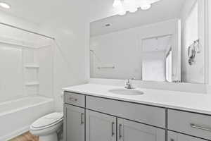 Full bath featuring wood finished floors, toilet, vanity, and shower / bathtub combination
