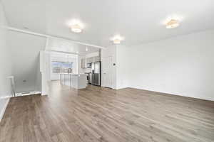 Unfurnished living room with light wood-style floors, baseboards, and a sink