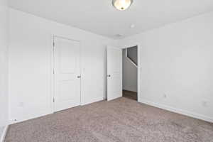 Unfurnished bedroom featuring baseboards, visible vents, and carpet
