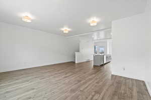 Unfurnished living room featuring visible vents, baseboards, wood finished floors, and a sink