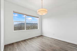 Empty room featuring wood finished floors, visible vents, baseboards, and a mountain view
