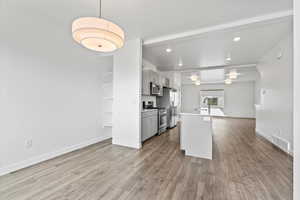 Kitchen with appliances with stainless steel finishes, gray cabinetry, wood finished floors, and visible vents