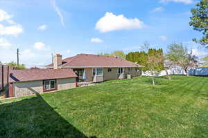 Rear view of property with fence, a chimney, and a yard