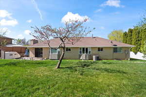 Back of property with brick siding, a lawn, a patio, and fence