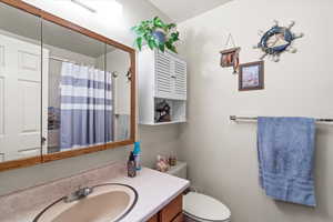 Full bath with vanity, curtained shower, and toilet