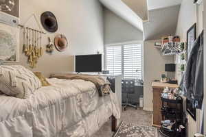 Bedroom featuring lofted ceiling, baseboards, carpet, and a textured ceiling