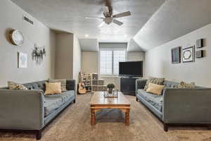 Living area with ceiling fan, a textured ceiling, and carpet