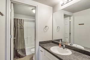 Full bath featuring tile floors, a textured ceiling, a vanity, a shower/bathtub combination, and a toilet