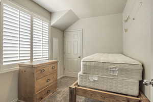 Bedroom featuring lofted ceiling, baseboards, carpet, and a textured ceiling