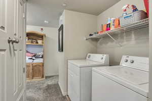 Washroom with a textured ceiling, baseboards, carpet, separate washer and dryer, and laundry area