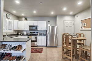 Kitchen featuring dark countertops, a sink, white cabinets, and appliances with stainless steel finishes