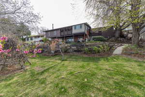 View of large, terraced back yard featuring fruit trees, large walnut tree, raspberry & blackberry bushes, grape vines, terraced garden, firepit area and swing set.