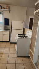 Kitchen featuring white cabinets, light countertops, white appliances, and light tile patterned floors