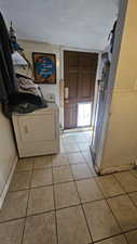 Laundry room featuring washer / dryer, a textured ceiling, and light tile patterned floors