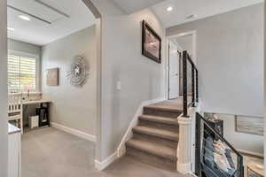 Staircase with arched walkways, baseboards, recessed lighting, and carpet flooring