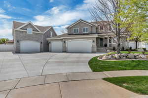 View of front facade with stone, stucco, an attached & detached garage, a front lawn, and driveway