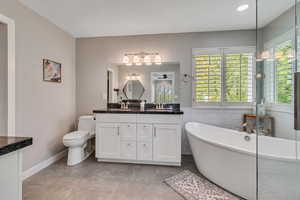Master bathroom featuring double sinks, separate makeup vanity, freestanding soaking tub and euro glass shower