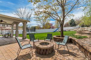 View of patio featuring a gas fire pit, commercial grade playground, and a trampoline