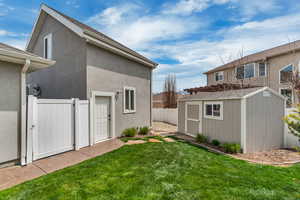 Fenced backyard with entrance to detached garage and garden shed