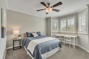 Carpeted bedroom featuring ceiling fan, bay window, and crown molding