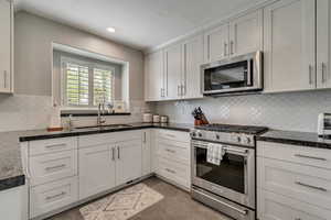 Kitchen with custom cabinets, tasteful backsplash, granite countertops, stainless steel appliances