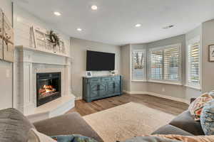 Family room with LVP flooring, a cozy raised hearth gas fireplace, baseboards, and recessed lighting