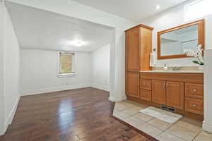 Bathroom with hardwood / wood-style flooring, baseboards, vanity, and visible vents