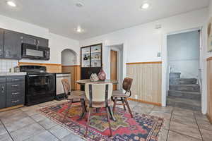 Dining space featuring a wainscoted wall, wood walls, arched walkways, and stairway