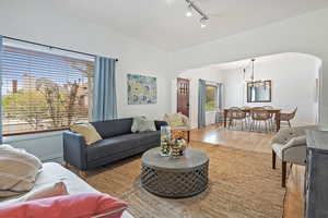 Living area featuring rail lighting, arched walkways, wood finished floors, and an inviting chandelier