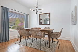 Dining space with a chandelier, wood-type flooring, and baseboards