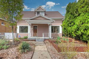 View of front facade featuring a shingled roof, a porch, and a vegetable garden