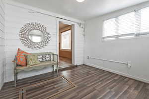 Sitting room with baseboards, wood finished floors, and a healthy amount of sunlight