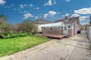 Back of house featuring a lawn, fence, and a deck