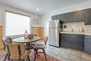 Kitchen with a textured ceiling, wooden walls, a wainscoted wall, light countertops, and freestanding refrigerator