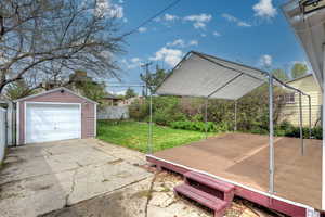 Exterior space with an outdoor structure, fence, a detached garage, and driveway