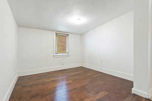 Spare room featuring dark wood-style floors, baseboards, a textured ceiling, and visible vents