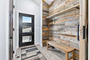 Mudroom featuring light wood finished floors and wood walls
