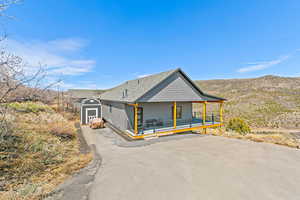 View of front facade featuring a storage shed, a deck with mountain view, an outdoor structure, and driveway