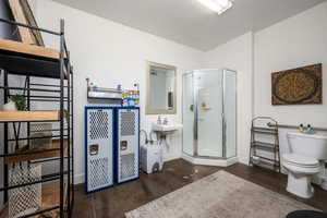Full bathroom with baseboards, concrete floors, a shower stall, and toilet