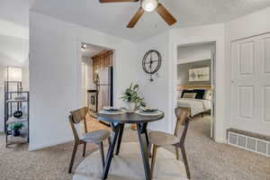 Dining space featuring light colored carpet, ceiling fan, and baseboards