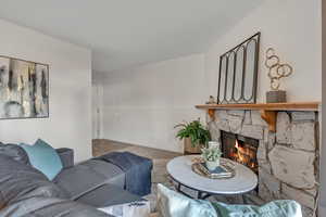 Living area featuring a stone fireplace and baseboards